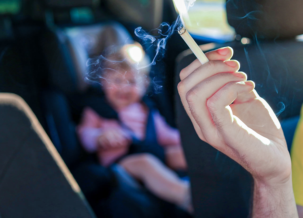 Ampel kippt Rauchverbot im Auto. Rauchender Autofahrer mit Kind.