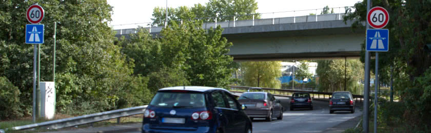 Mehrere Fahrzeuge die eine Autobahnauffahrt mit Tempolimit befahren.