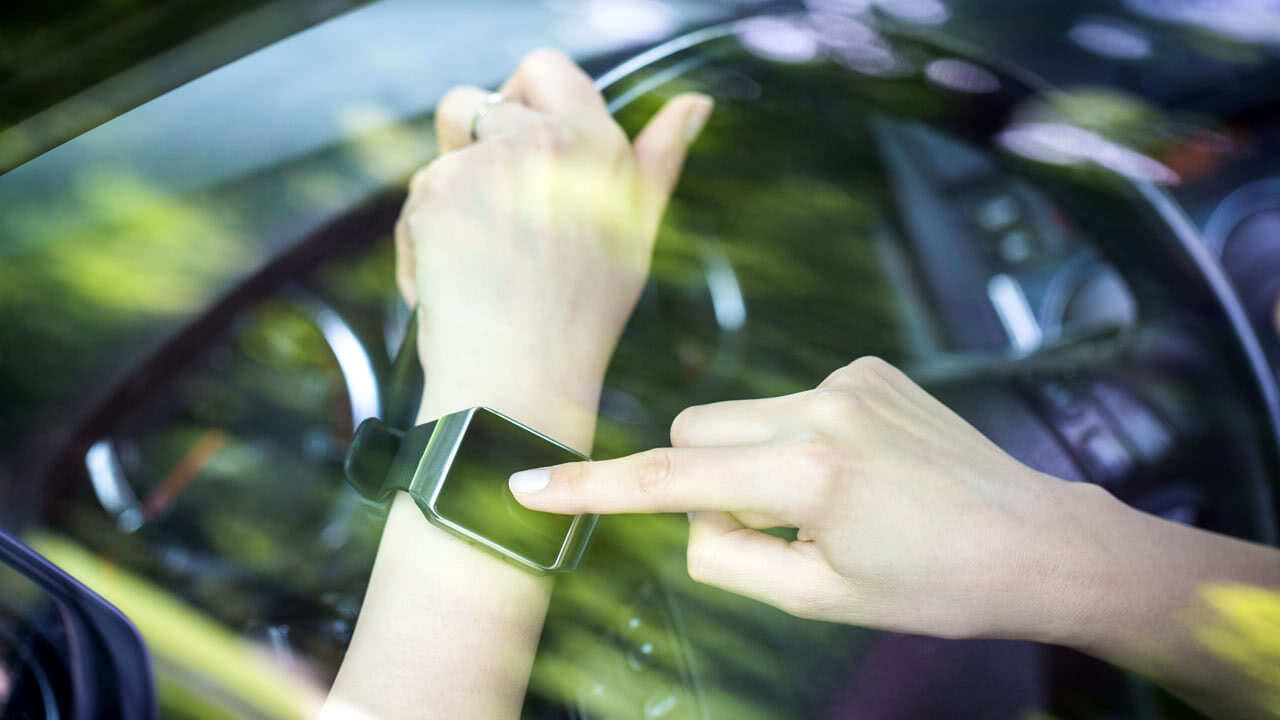 Frau nutzt Smartwatch beim Autofahren.