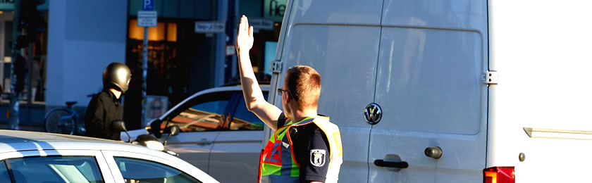 Handzeichen von einem Polizisten an einer Kreuzung.