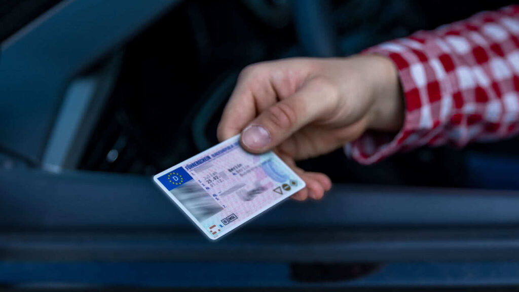 Person reicht Führerschein aus dem Auto. Die Führerscheinprüfung soll nun refomiert werden.
