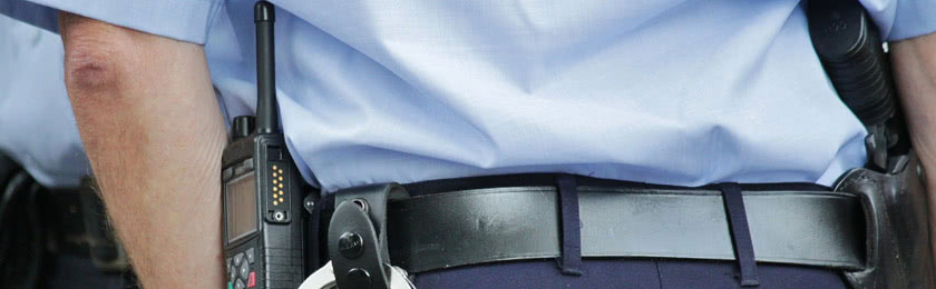 Ein Polizist in Uniform von hinten fotografiert, der im Zuge einer Anhörung eine Person auf die Polizeiwache vorlädt