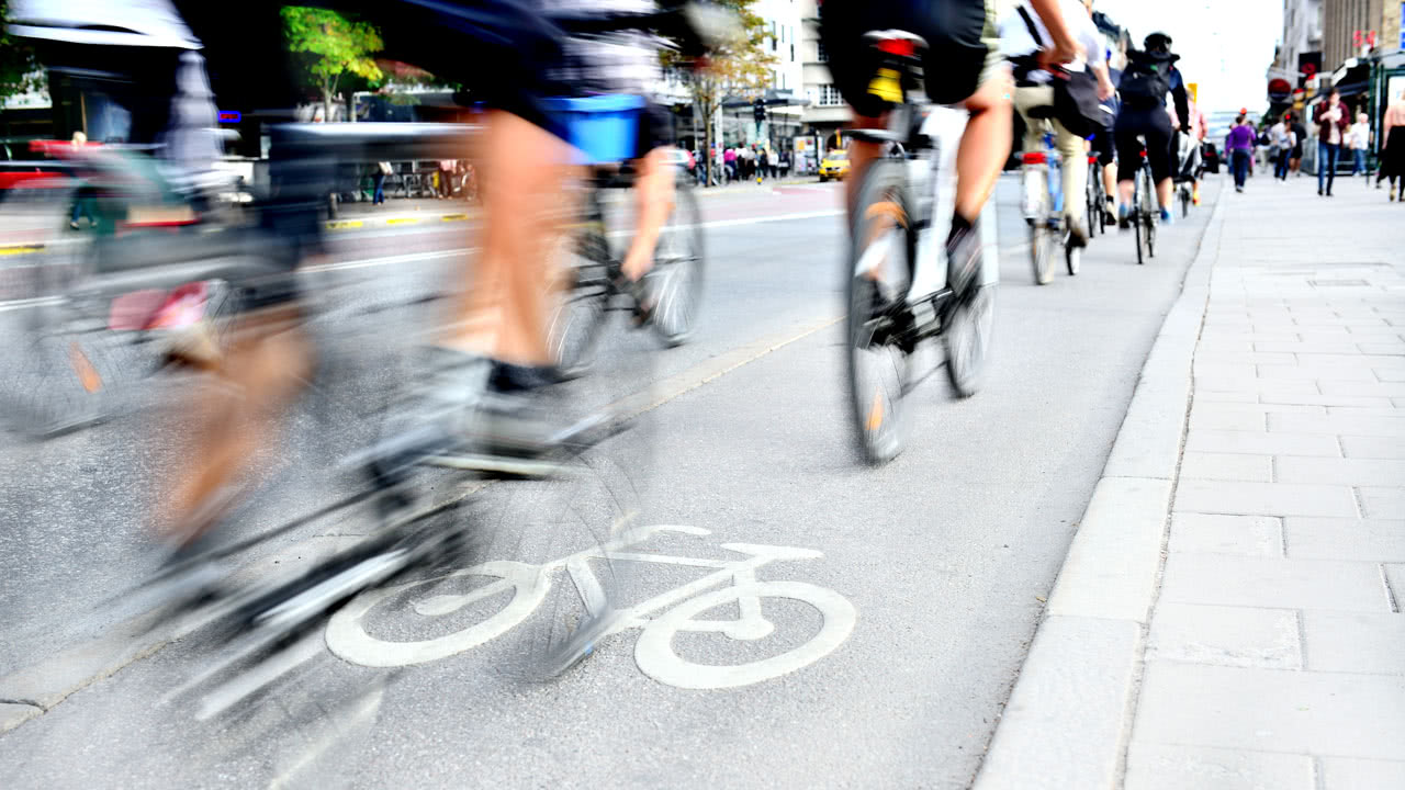 Fahrradfahrer durchfahren eine Straße, die durch ein Tempolimit reguliert ist.