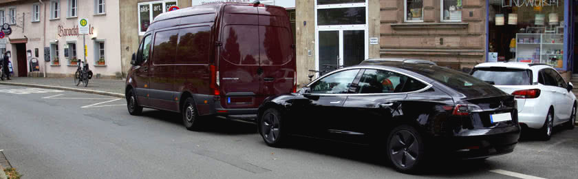 Ein E-Auto und ein Transporter auf der Straße parken andere Fahrzeuge zu