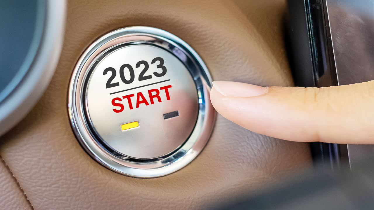 Person drückt den Startknopf in einem Auto für das Jahr 2023.